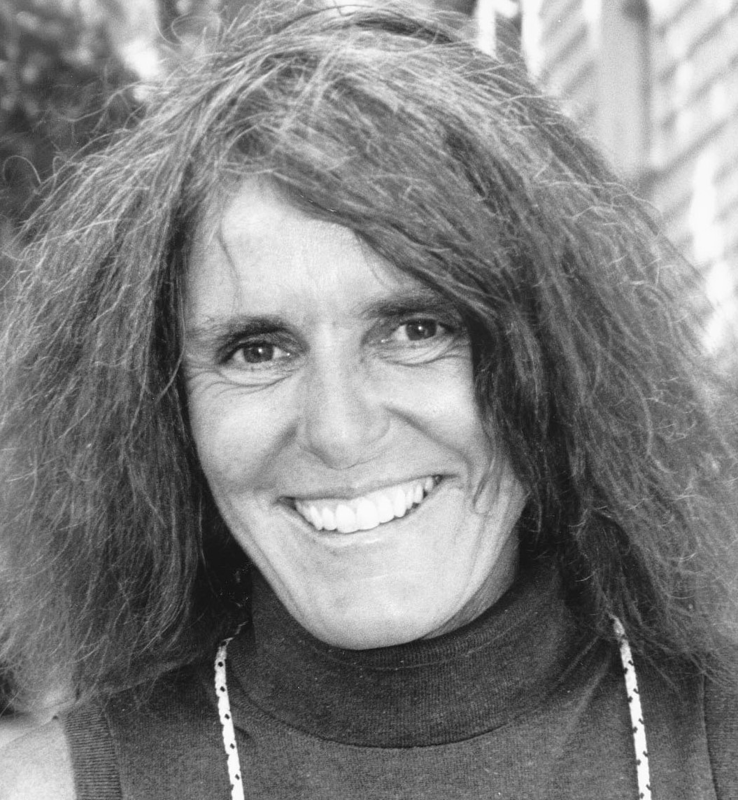 Headshot of Joy WIlliams, with a bright smile and long, loose hair, wearing a turtleneck sweater.
