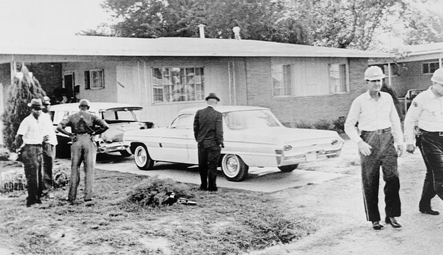 Medgar Evers house with two cars in driveway and several unidentified men, some white and some black, walking or standing.