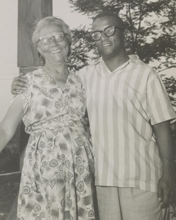 Strayhorn with his right arm around his mother, both standing and looking at photographer. Image in black and white.